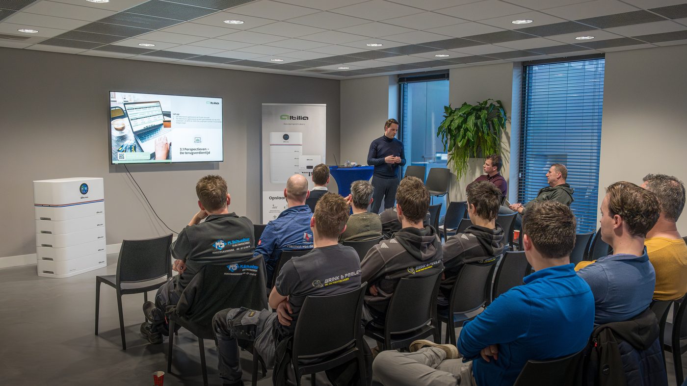 Installateurs volgen een training van Altilia, met een presentatie op het scherm en een thuisbatterij in de zaal