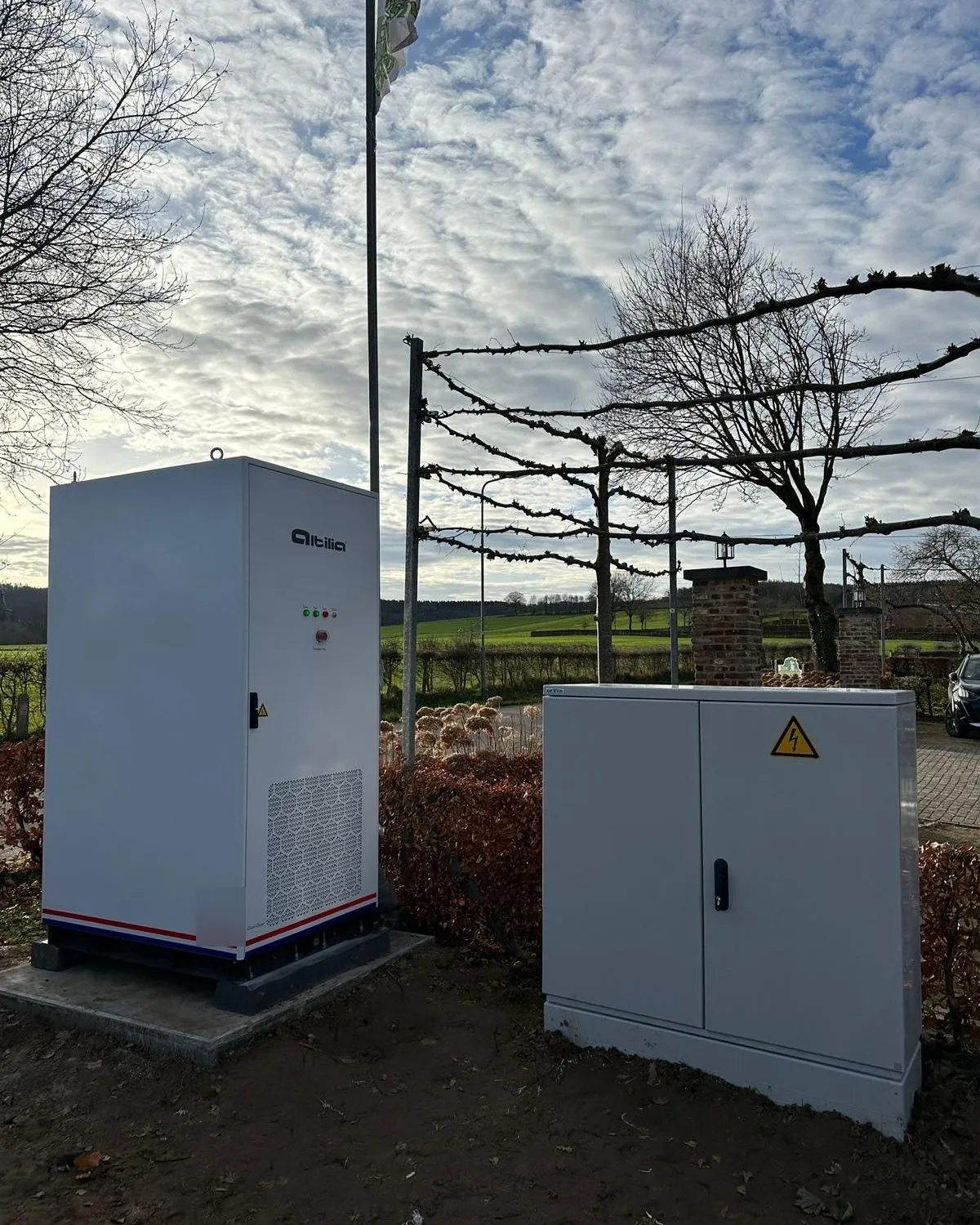 Vloeistofgekoelde Altilia energiekast buiten op een betonplaat, naast een aparte verdeelkast