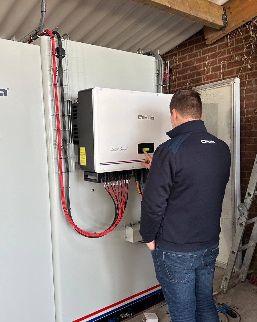 Monteur van Altilia stelt de omvormer in aan de zijkant van een energiekast in een schuur