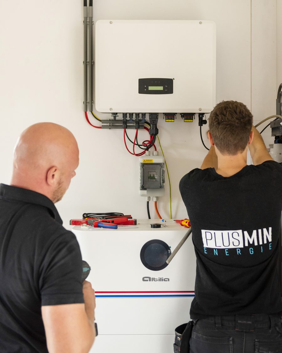 Twee installateurs sluiten een omvormer boven een Altilia stapelbatterij aan