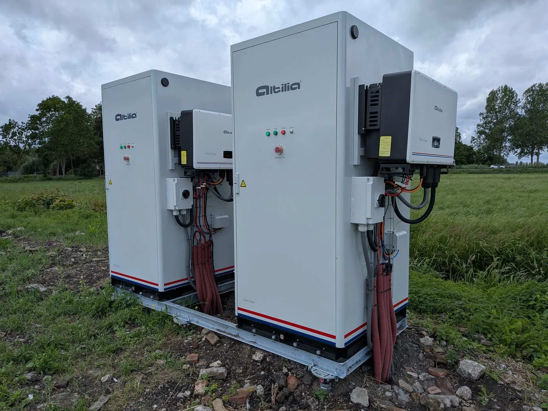 Twee energiekasten van 112 kWh op een stalen frame in een weiland, elk met de omvormer aan de zijkant