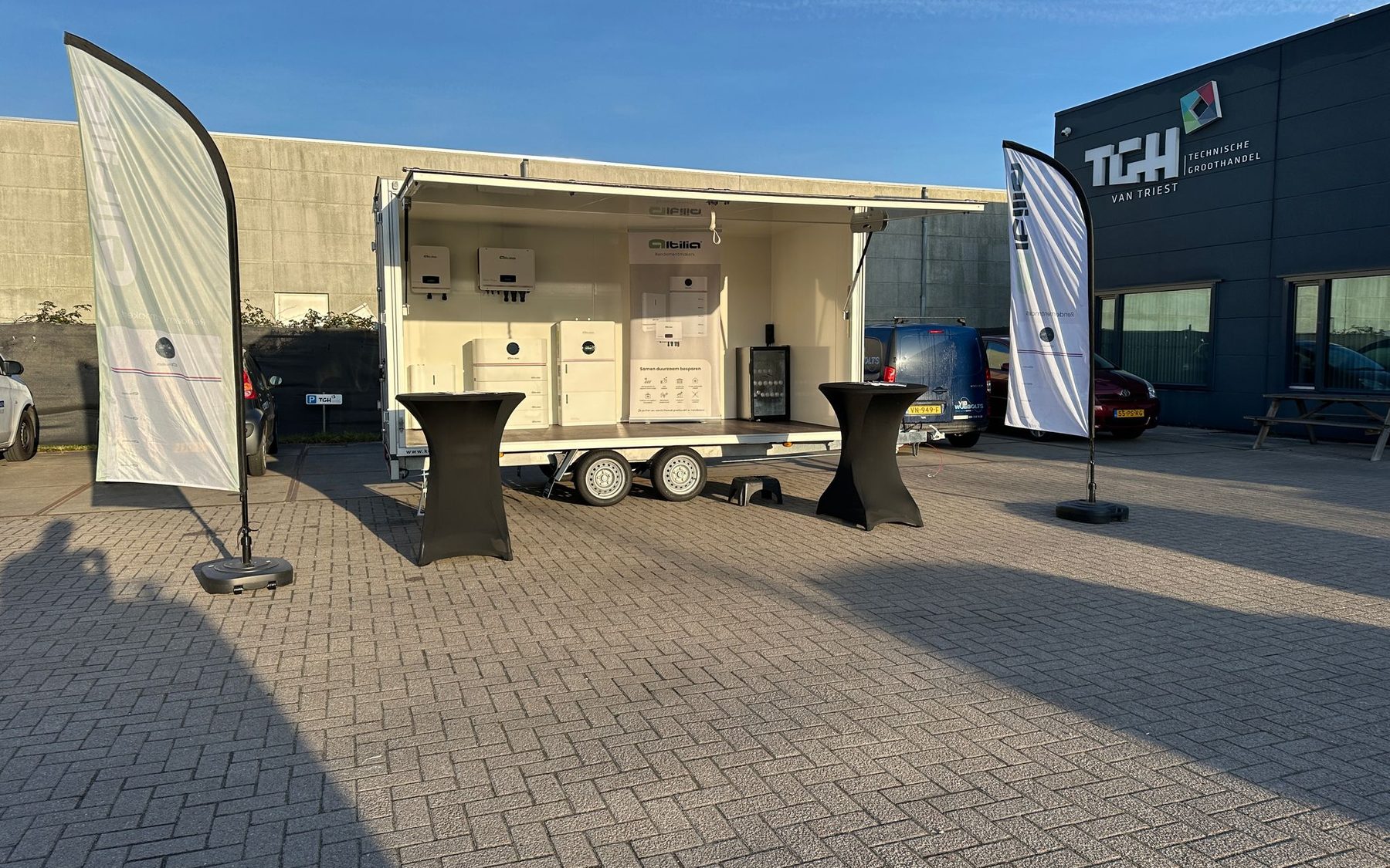 De showroomtrailer van Altilia met thuisbatterijen en omvormers op het terrein van een technische groothandel